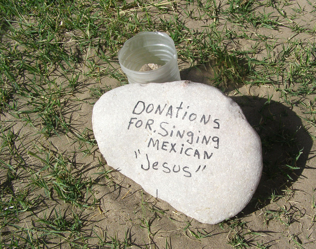 A rock that says, Donations for singing Mexican Jesus.