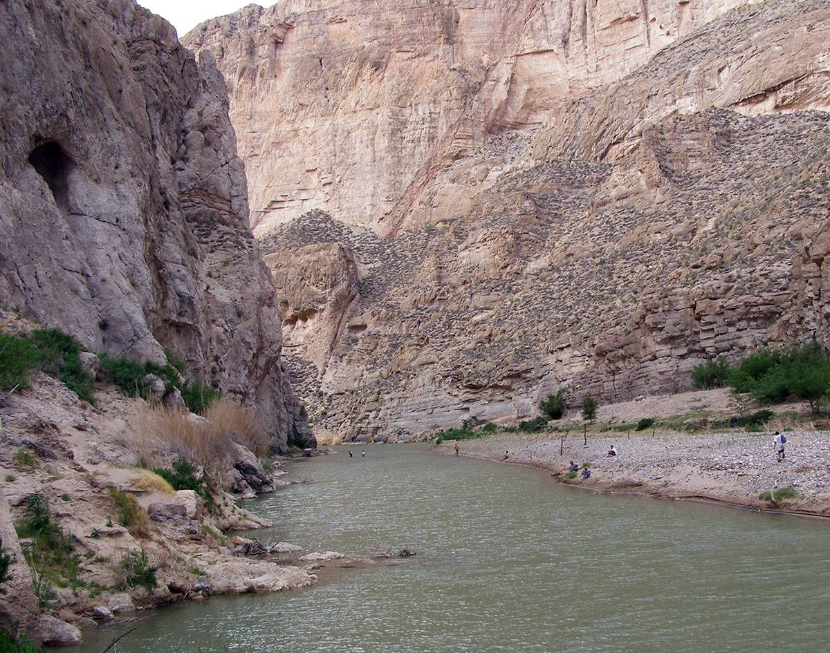 A long shot of people dotting the river shore.