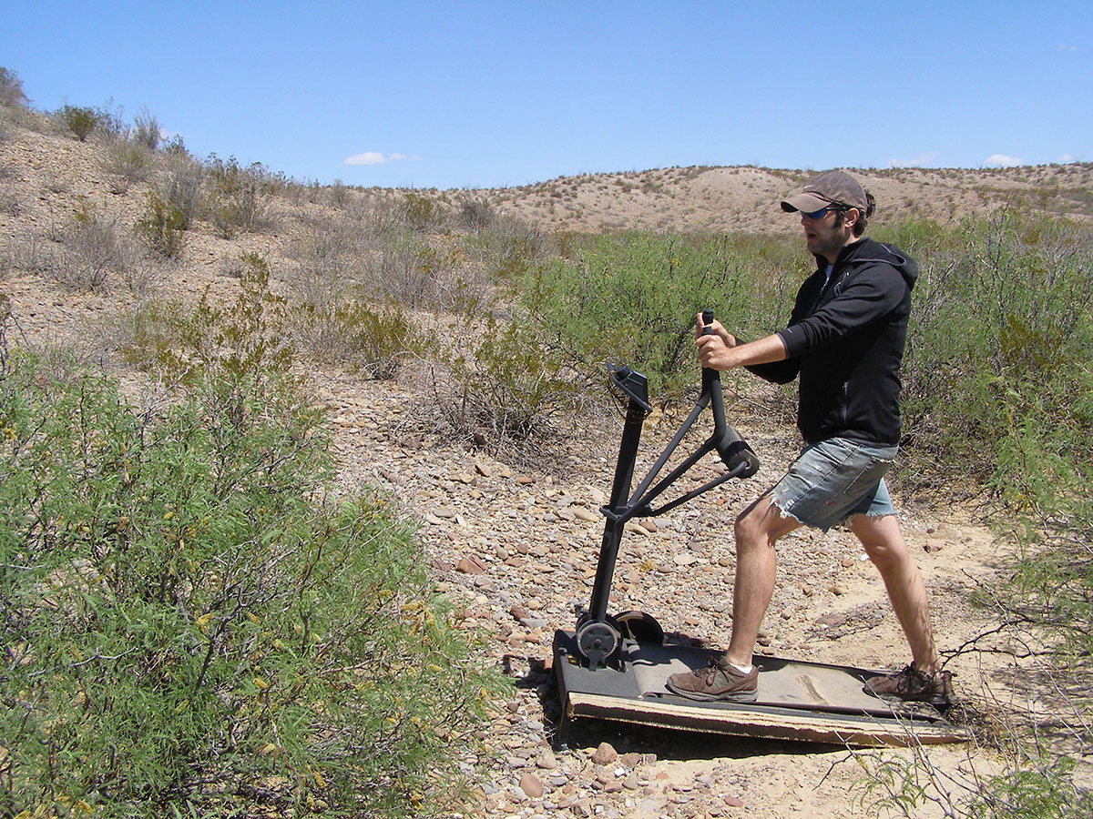 Arthur pretending to use a broken down treadmill in the middle of the desert.