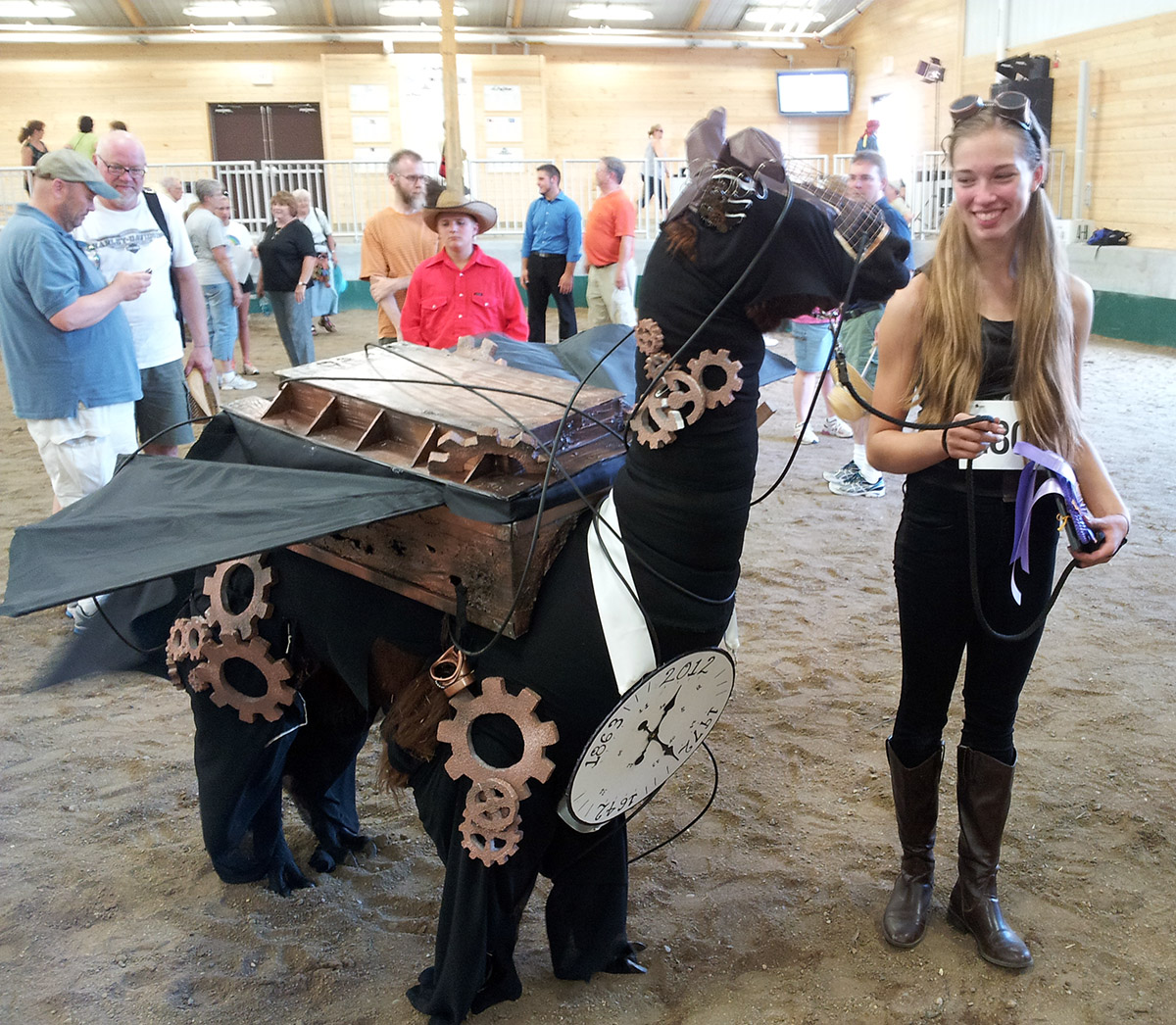 Annaliese with her award, smiling at Steampunk Time Machine Llama.
