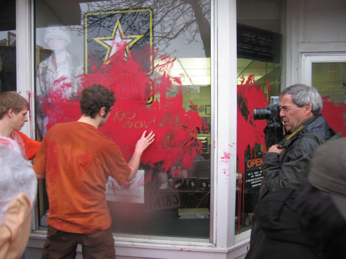 Man smearing red paint on the Army recruiter office.