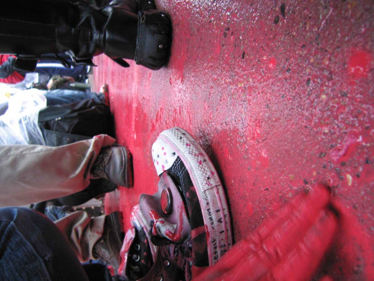 Black converse shoe covered in red paint