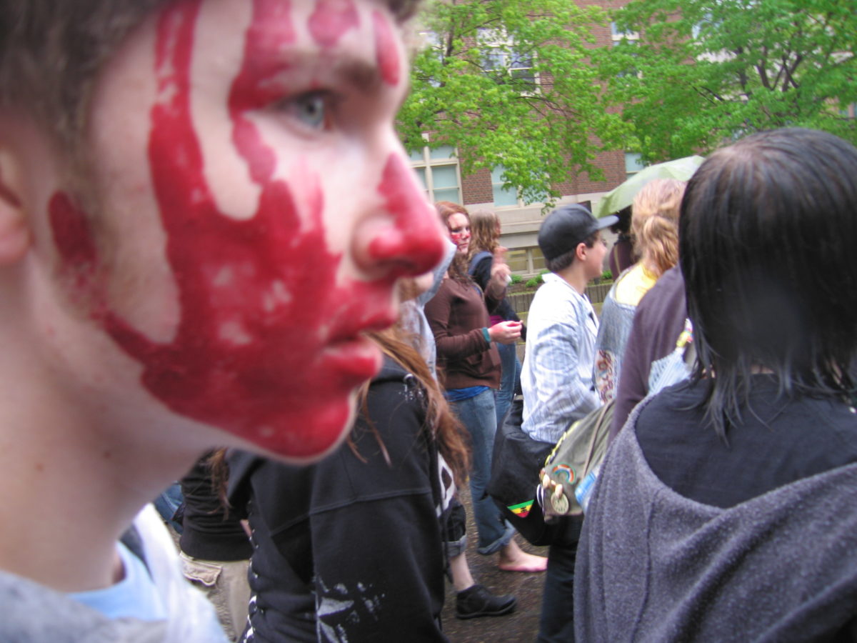 Teenager with a red paint handprint on his face.