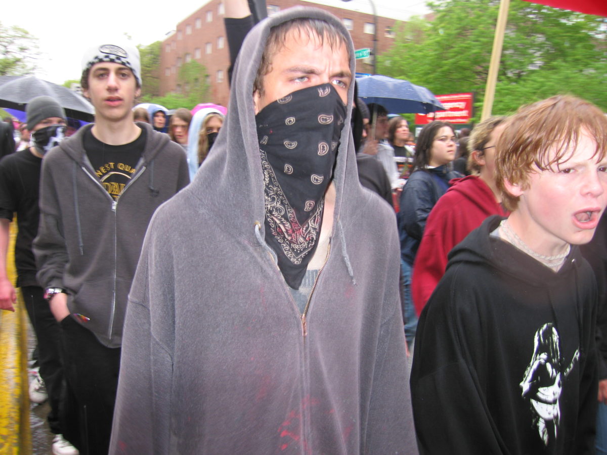 Fierce looking protester with black bandana around his face.