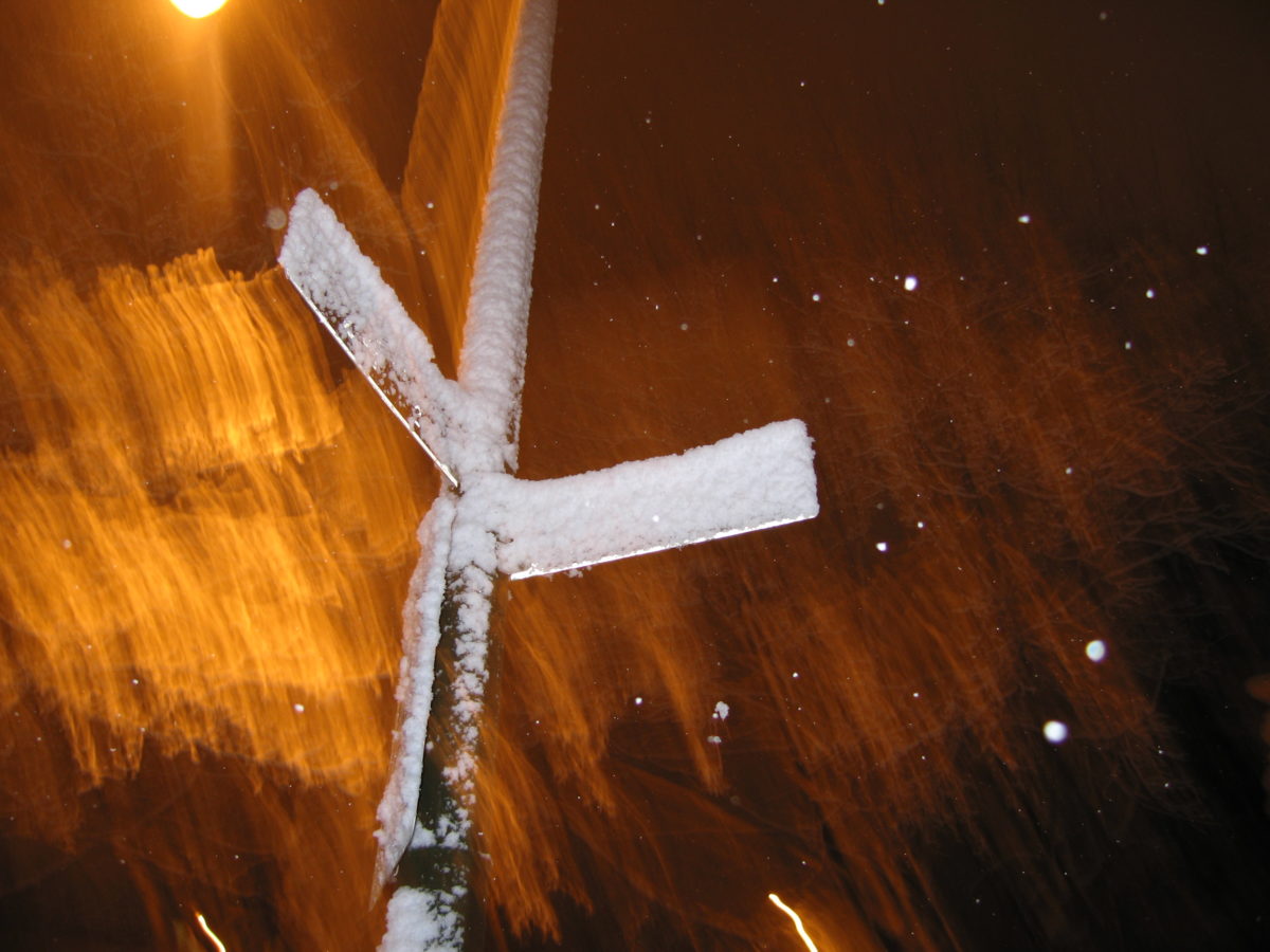 Snow covered streetsigns with night light.