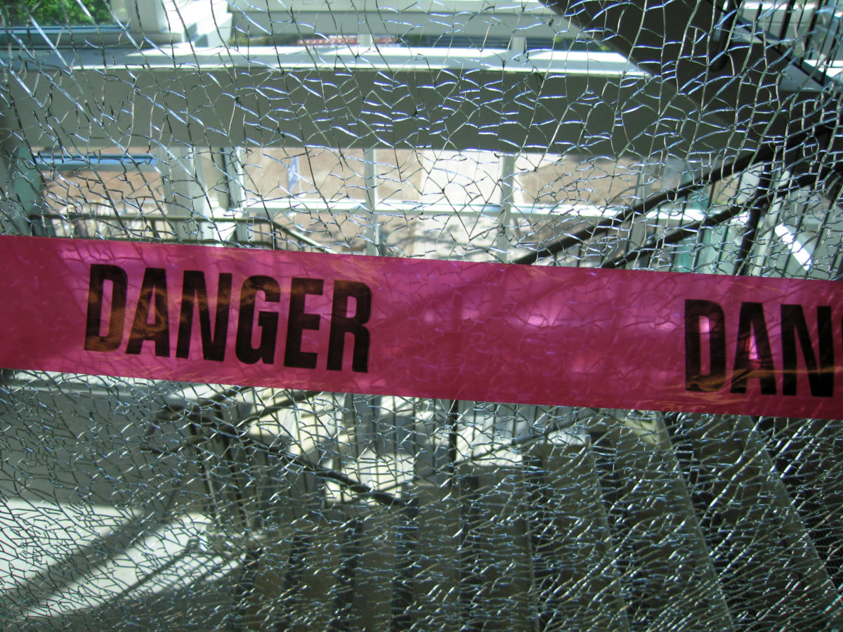 Caution tape over shattered glass.