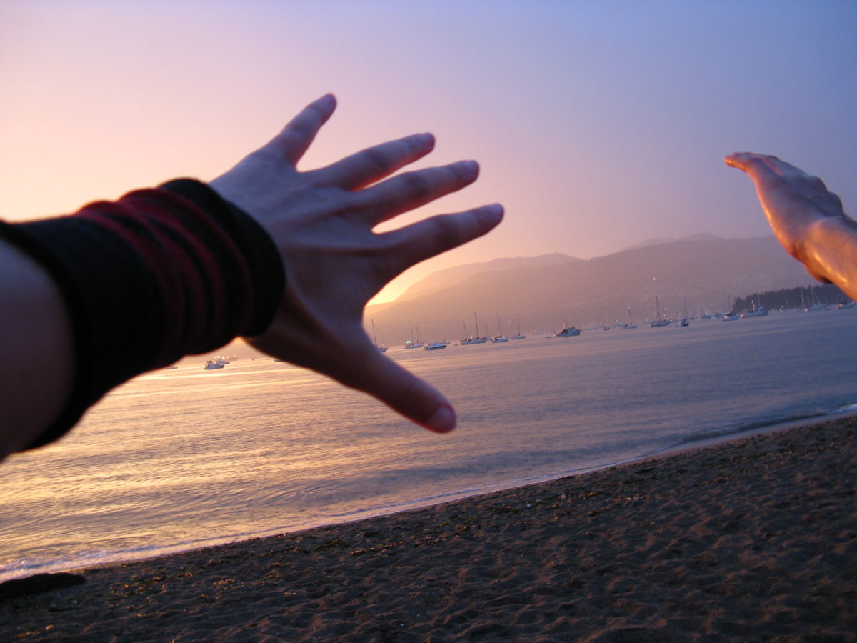 Hands reaching for the sunset horizon