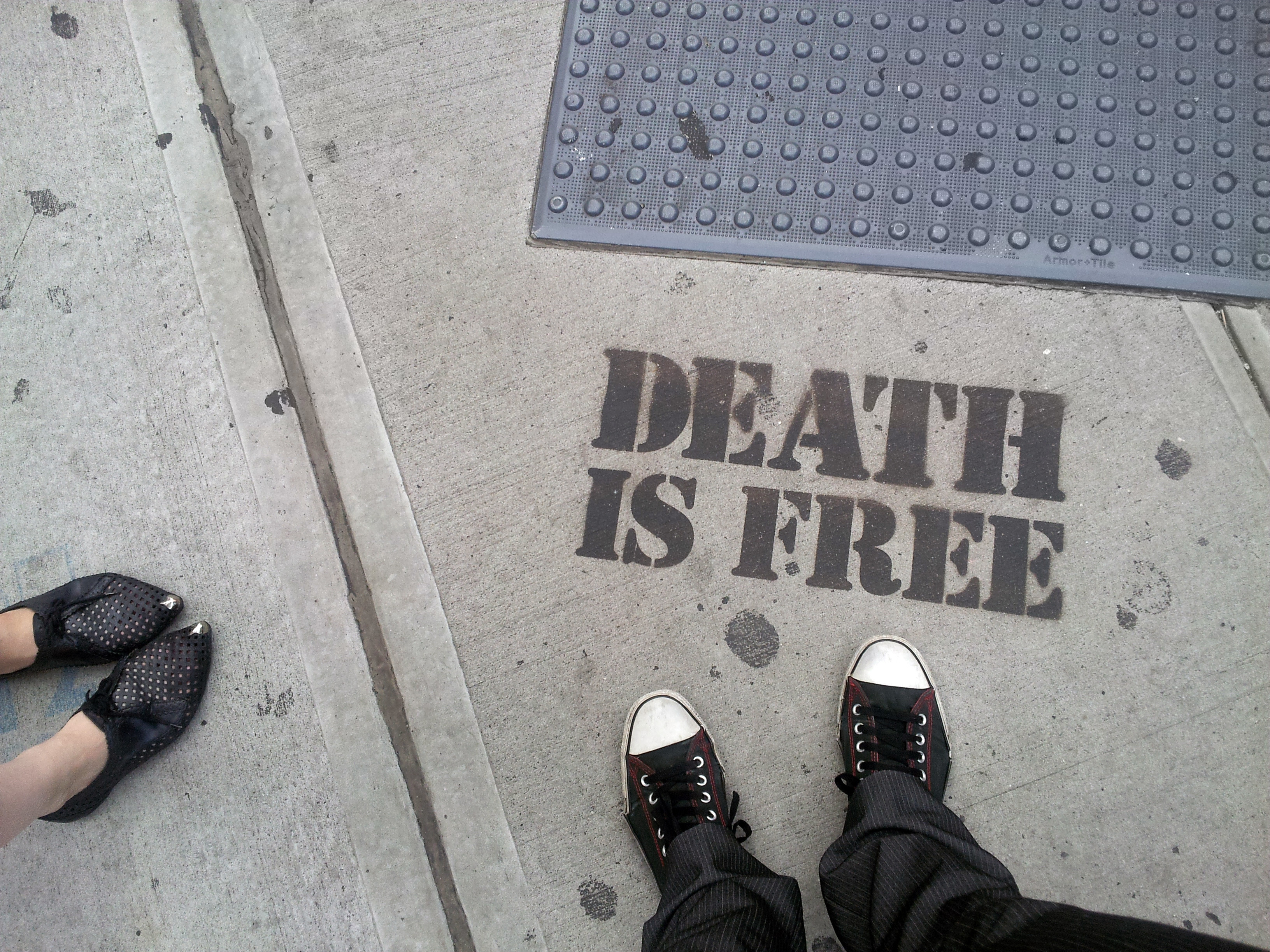 Street stencil that says Death is Free. Anna and my shoes are visible.