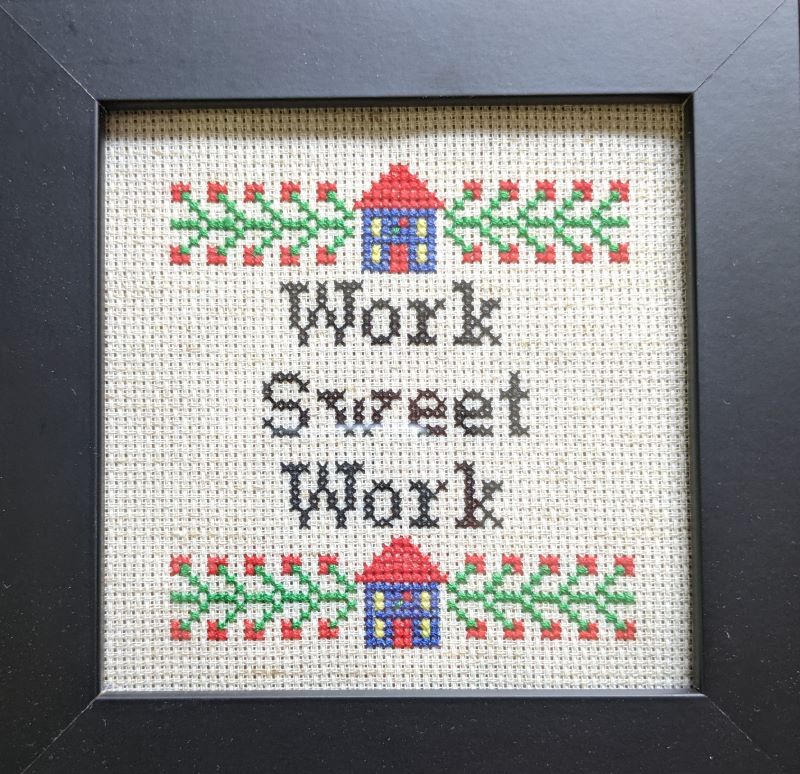 A handmade cross-stitch that reads Work Sweet Work.