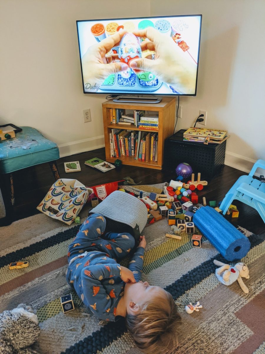 Louie surrounded by toys staring at the TV.