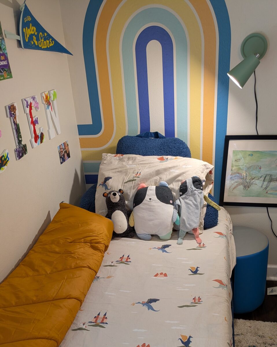 A child's bed with Target sheets, pillows, and a sleeping bag.
