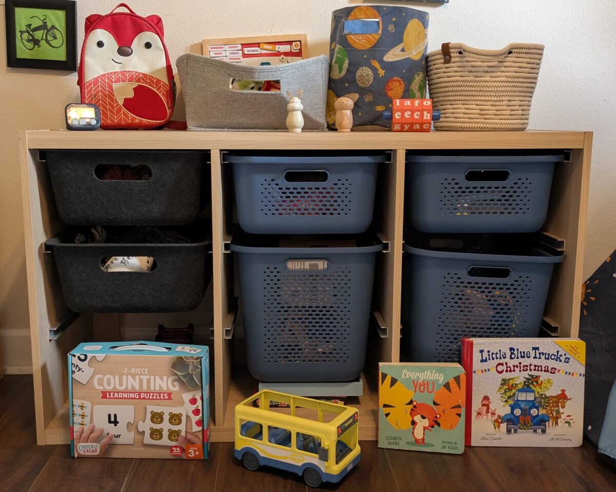 A storage unit with slide-out baskets and toys, all from Target.