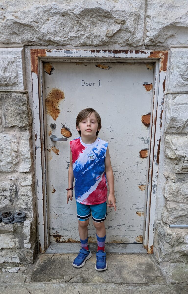 Boy with closed eyes in front of a creepy door